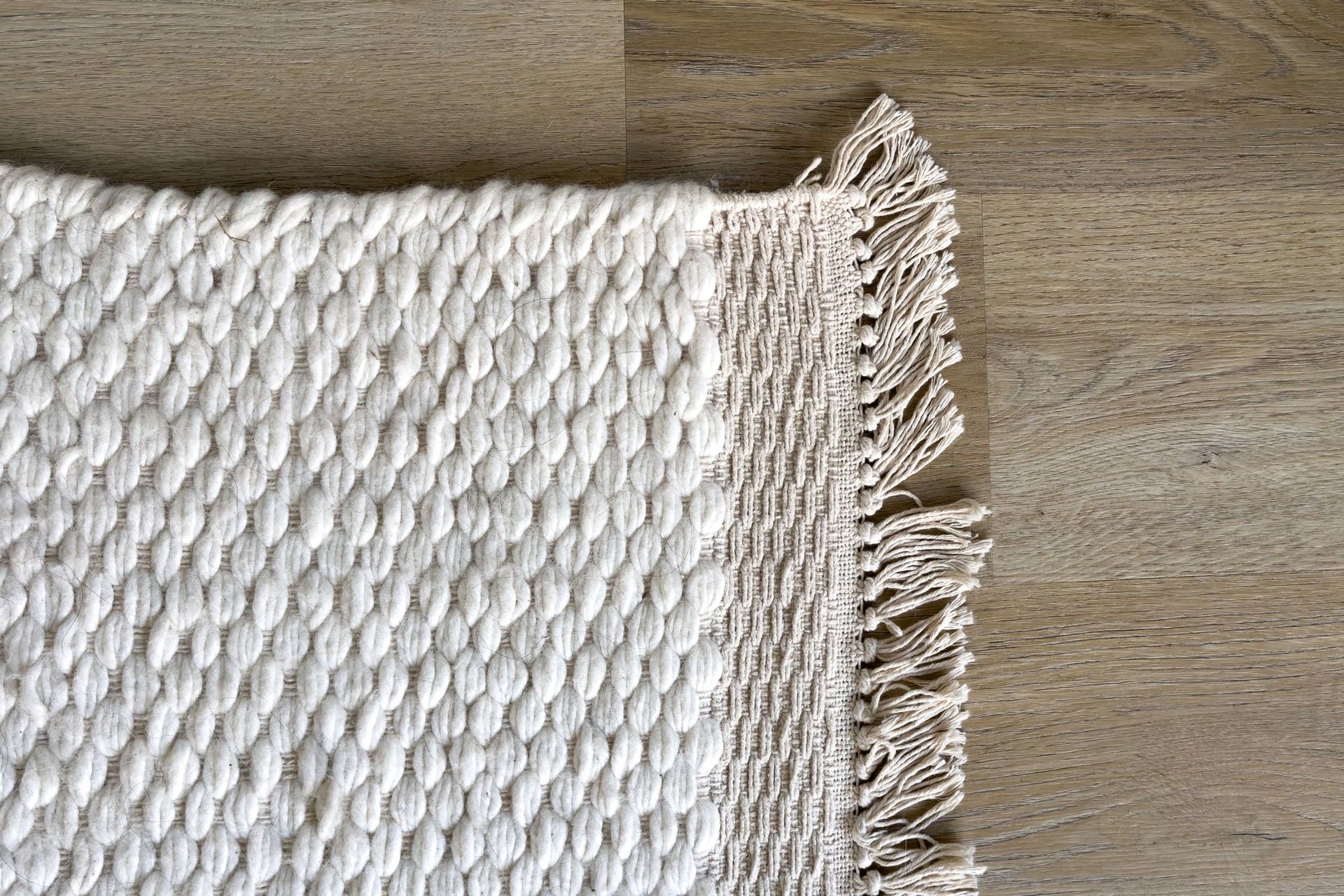 White woven rug with fringe detail, top view
